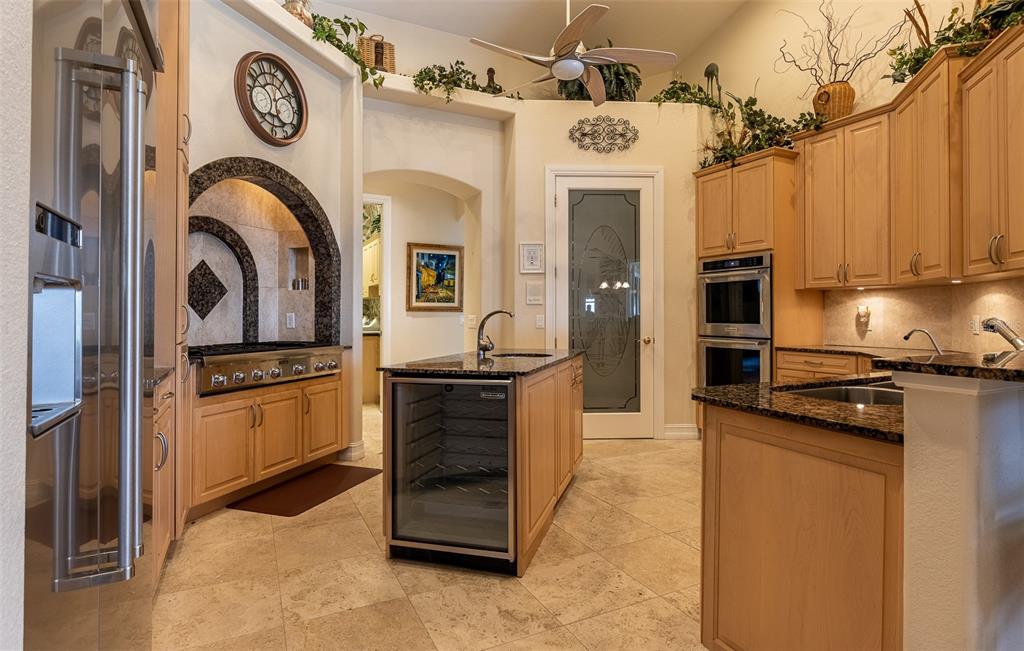 A kitchen features light wood cabinets, granite countertops, a central island, and a stainless refrigerator — 17479 OHARA DRIVE, PORT CHARLOTTE, FL