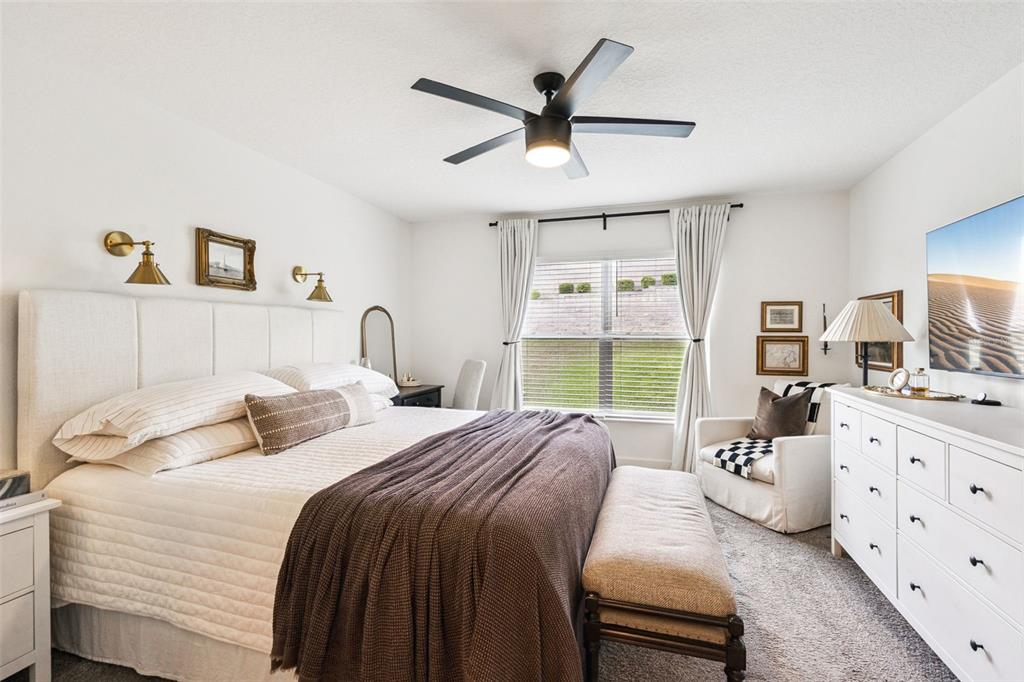 A bedroom features a bed with a brown throw, a white dresser, and a ceiling fan — 1657 WILSON PRAIRIE CIRCLE, GROVELAND, FL
