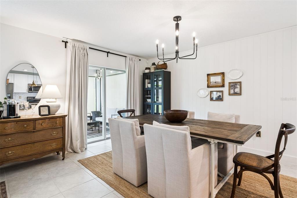 A dining room features a wooden table, upholstered chairs, a chandelier, and a sliding glass door — 1657 WILSON PRAIRIE CIRCLE, GROVELAND, FL