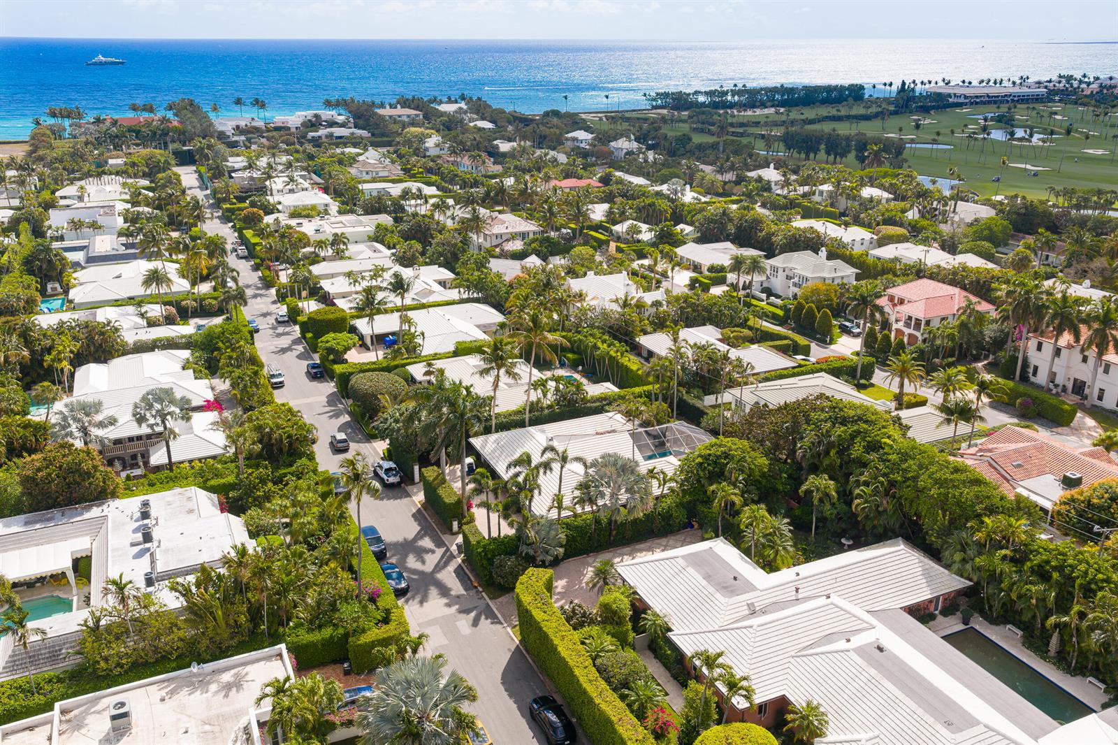 An aerial view shows a residential neighborhood with white-roofed houses, lush landscaping, and a nearby ocean — 280 Tradewind Drive, Palm Beach FL 33480, PALM BEACH, FL