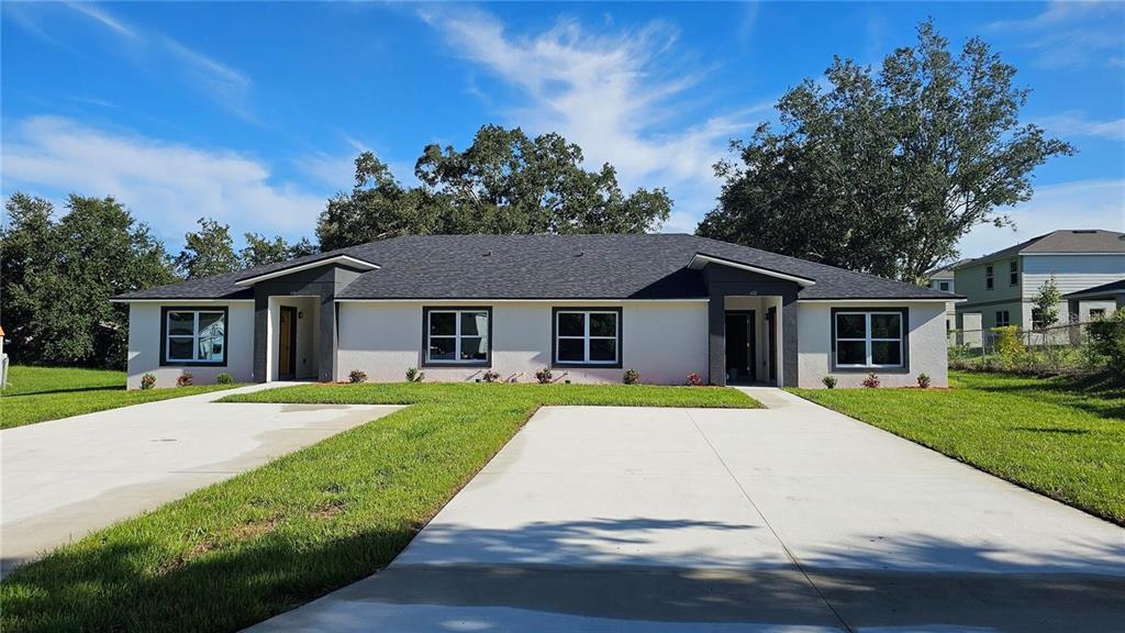 A single-story duplex with a light-colored stucco exterior, dark trim, and two concrete driveways — 604 LIME AVENUE, DUNDEE, FL
