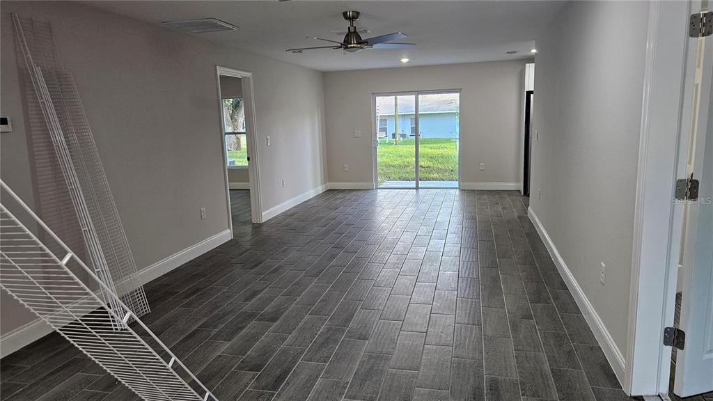 An empty room with gray wood-look tile flooring, a ceiling fan, and sliding glass doors — 604 LIME AVENUE, DUNDEE, FL