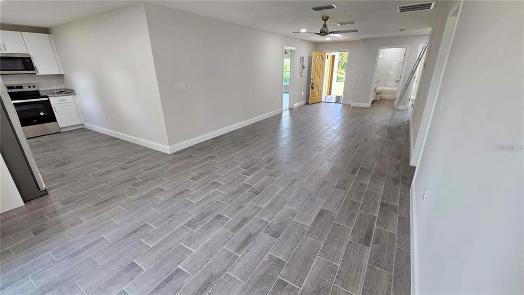 An open-concept living area features gray wood-look tile flooring and a kitchen with white cabinets — 604 LIME AVENUE, DUNDEE, FL