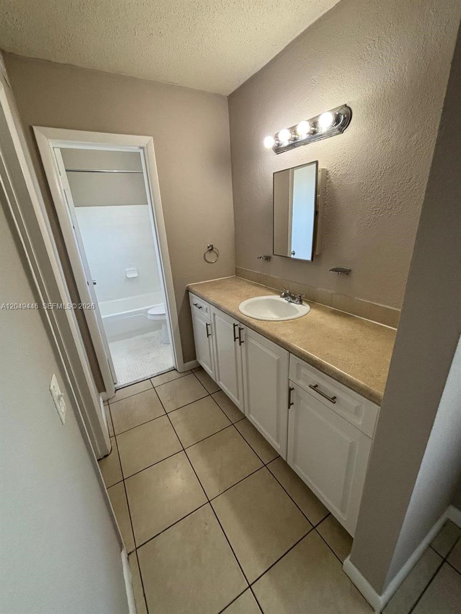 A bathroom features a white vanity with a tan countertop, tiled floors, and a mirror — 3050 S Dixie Hwy # 402, Miami FL 33133, MIAMI, FL