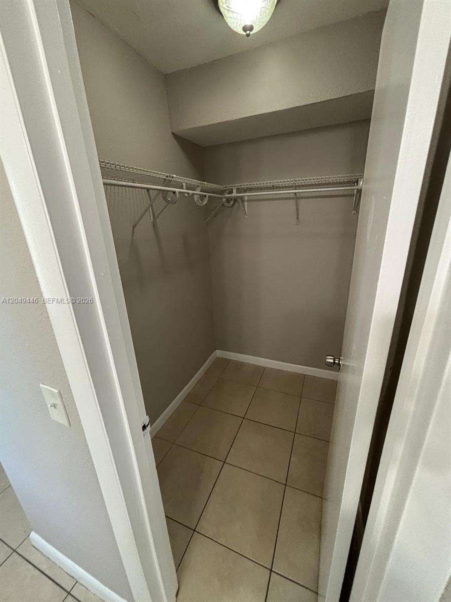 A small walk-in closet features beige tile flooring, light gray walls, and white wire shelving — 3050 S Dixie Hwy # 402, Miami FL 33133, MIAMI, FL