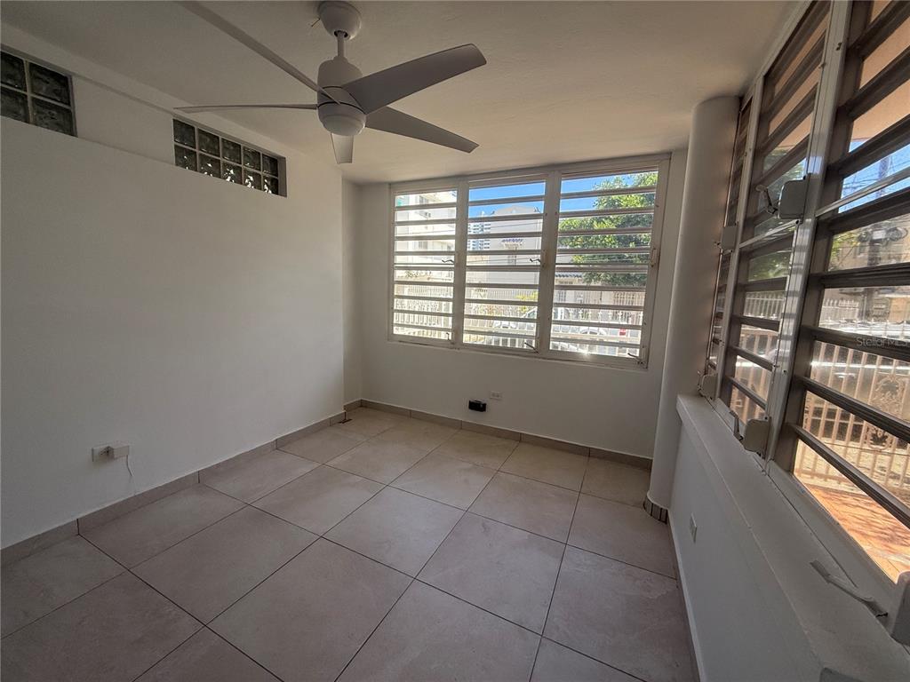 An empty room with light tile flooring, a ceiling fan, and louvered windows — 1510 LAS MARÍAS ST., SAN JUAN, PR