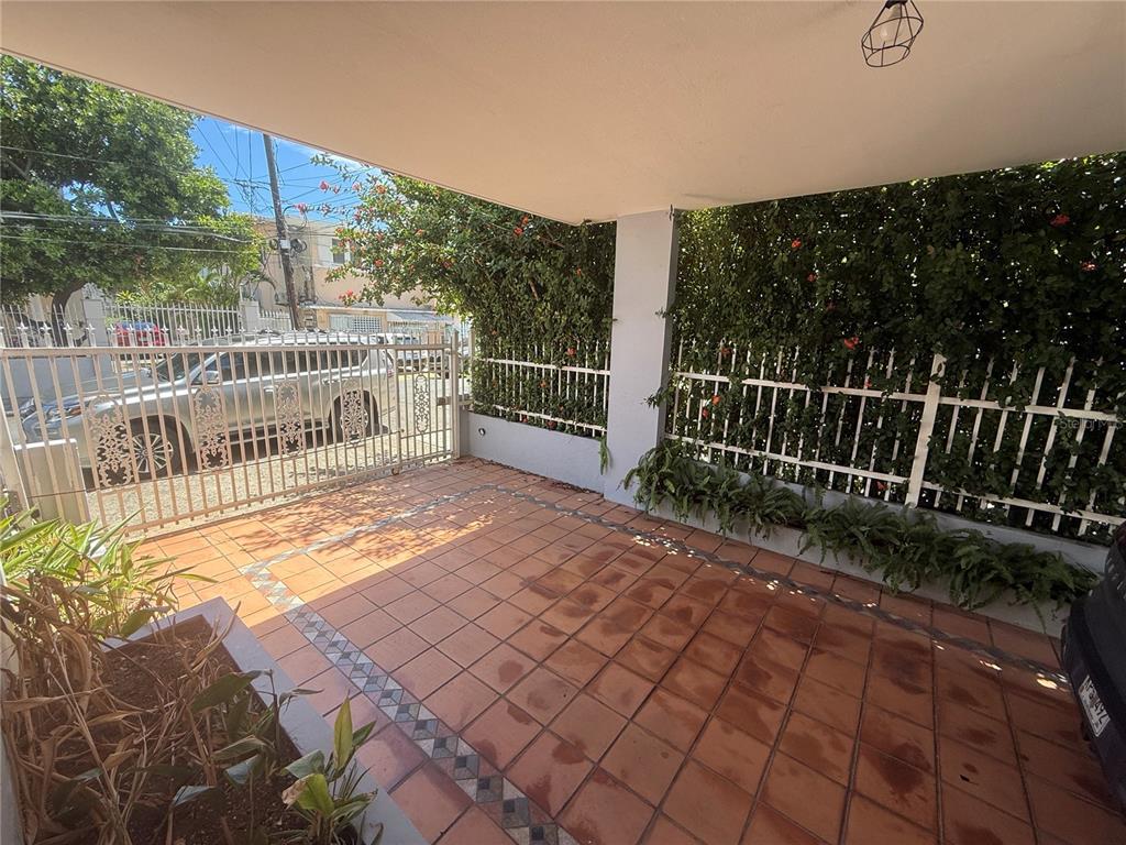 A covered patio features terracotta tile flooring, a white metal fence, and surrounding greenery — 1510 LAS MARÍAS ST., SAN JUAN, PR