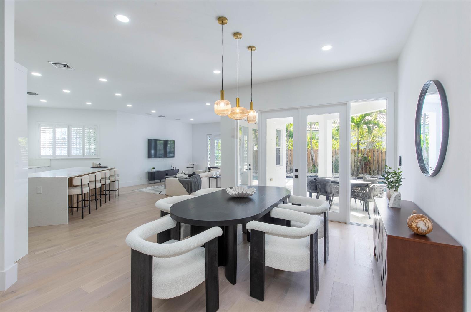 A dining area with a dark oval table, white chairs, and glass doors to a patio — 2443 Players Ct, Wellington FL 33414, WELLINGTON, FL