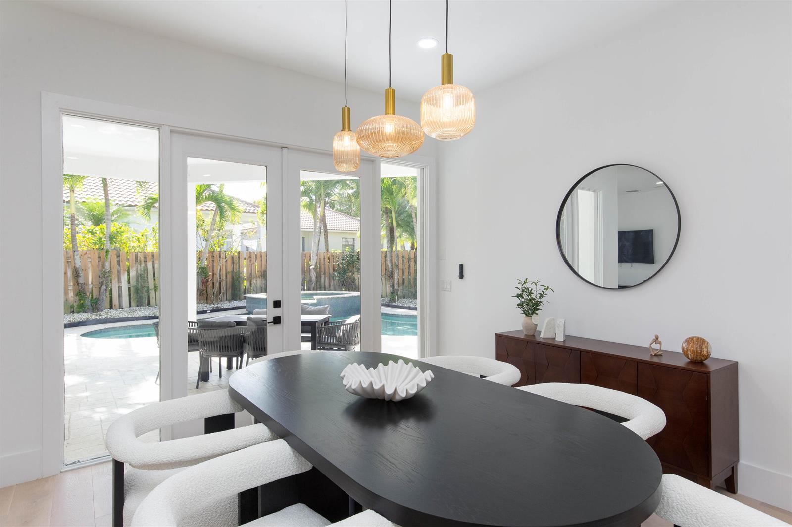 A dining room features a black oval table, white chairs, and a view of a pool — 2443 Players Ct, Wellington FL 33414, WELLINGTON, FL