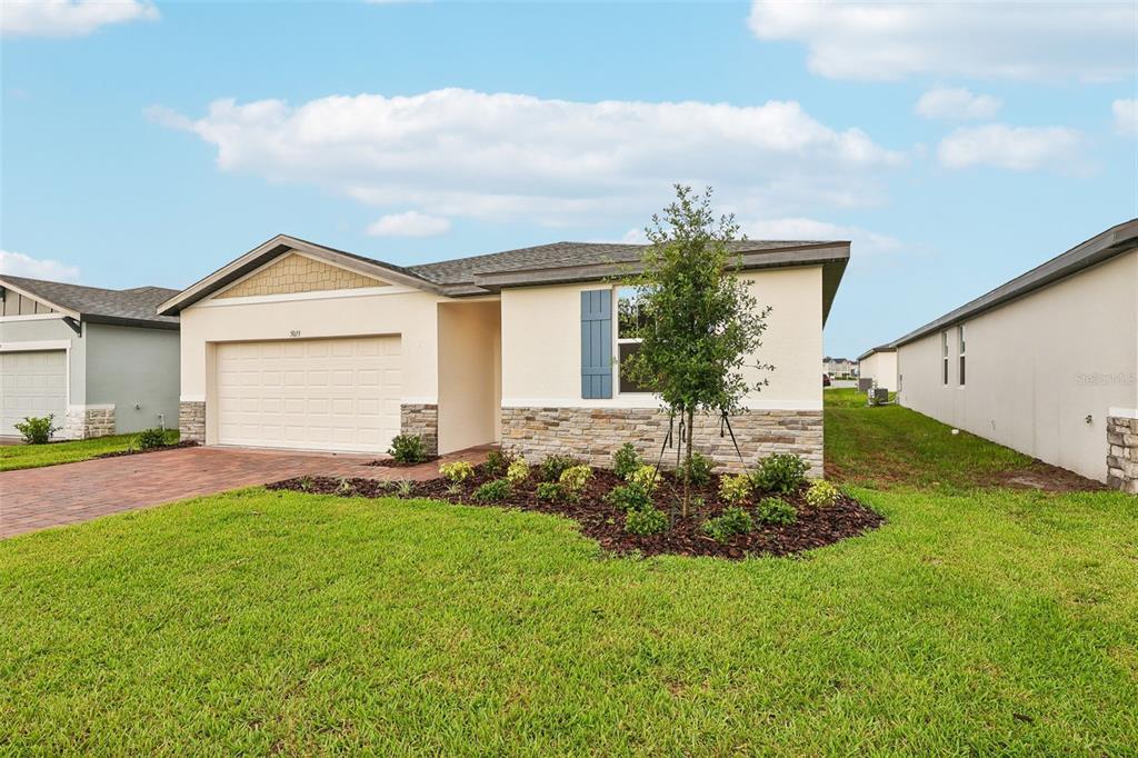 A single-story house with a two-car garage, stone veneer accents, and a landscaped front yard — 5013 KAIA AVENUE, WINTER HAVEN, FL