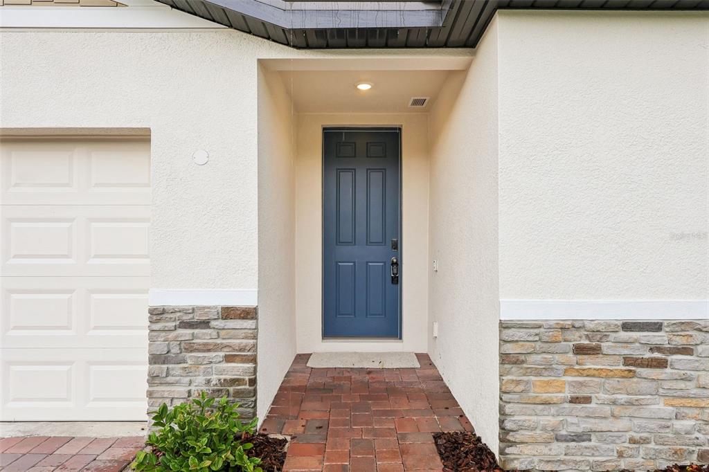 A blue front door is centered in a recessed entryway with stone veneer and stucco — 5013 KAIA AVENUE, WINTER HAVEN, FL