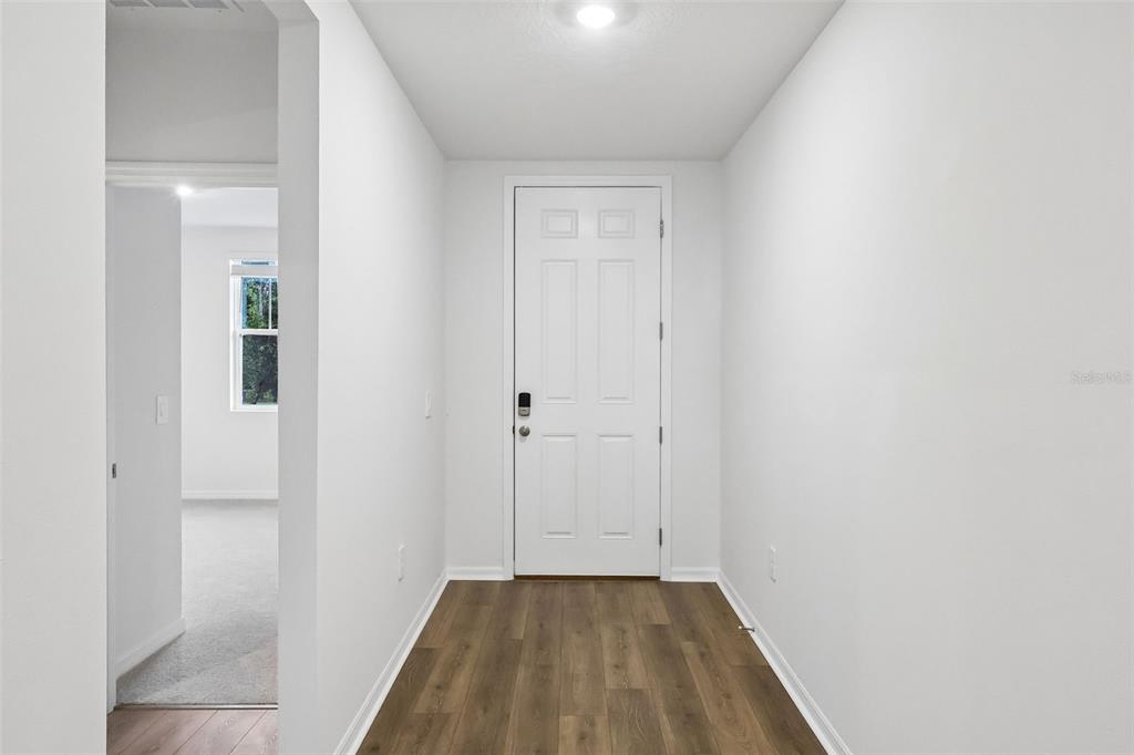 A white front door opens into a small entryway with wood-look flooring — 5013 KAIA AVENUE, WINTER HAVEN, FL