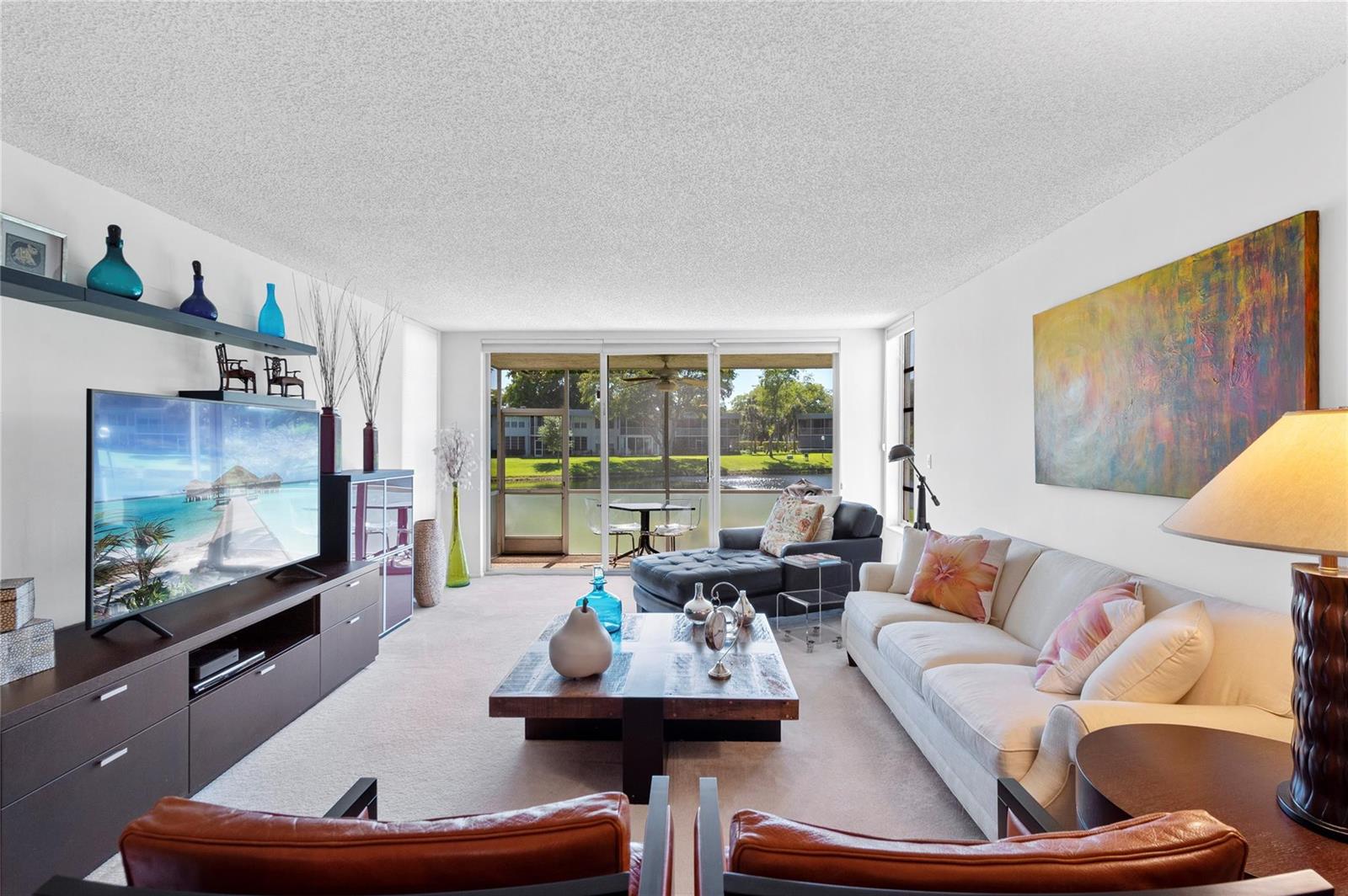 A living room features a white sofa, a wooden coffee table, and a sliding glass door — 4240 Oaks Terrace # 105, Pompano Beach FL 33069, POMPANO BEACH, FL