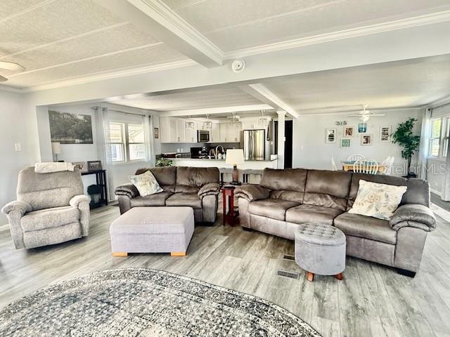 A living room features gray furniture, light wood-look flooring, and an open kitchen area — 264 PHILADELPHIA BOULEVARD UNIT 51, PALM HARBOR, FL