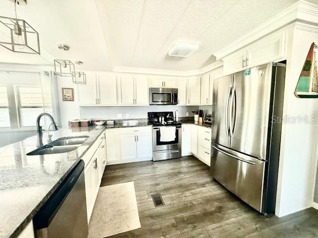 A kitchen features white cabinetry, stainless steel appliances, and a large granite-topped island — 264 PHILADELPHIA BOULEVARD UNIT 51, PALM HARBOR, FL