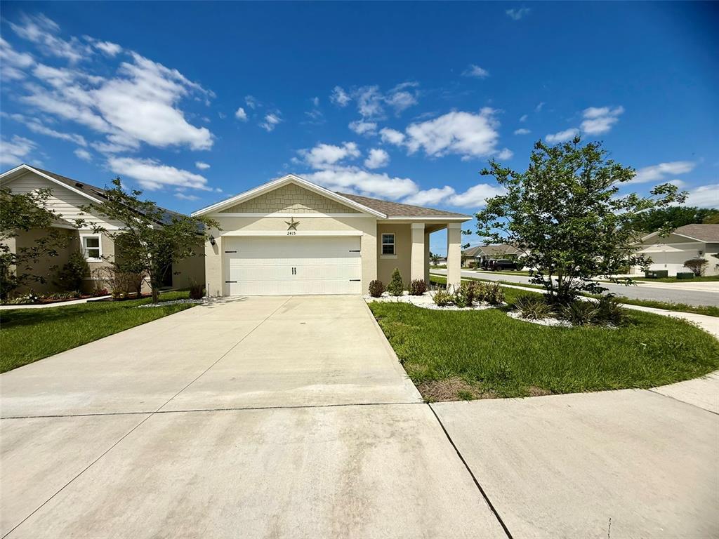 A single-story house with a beige exterior, a two-car garage, and a concrete driveway — 2415 BRASSIE COURT, WINTER HAVEN, FL