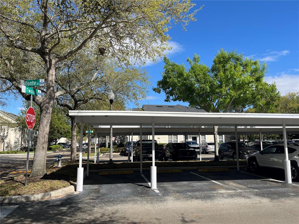 A covered parking structure with multiple spaces sits next to a street sign and trees — 3190 DANTE DRIVE UNIT 308, ORLANDO, FL