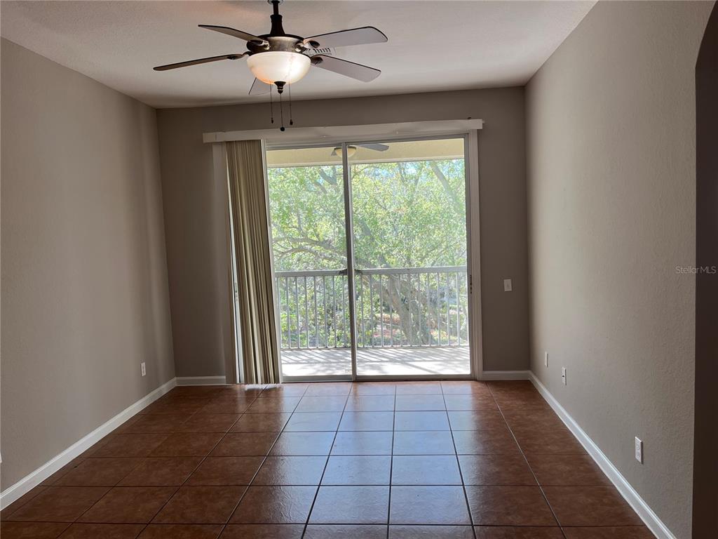 An empty room features brown tile flooring, a ceiling fan, and a sliding glass door — 3190 DANTE DRIVE UNIT 308, ORLANDO, FL