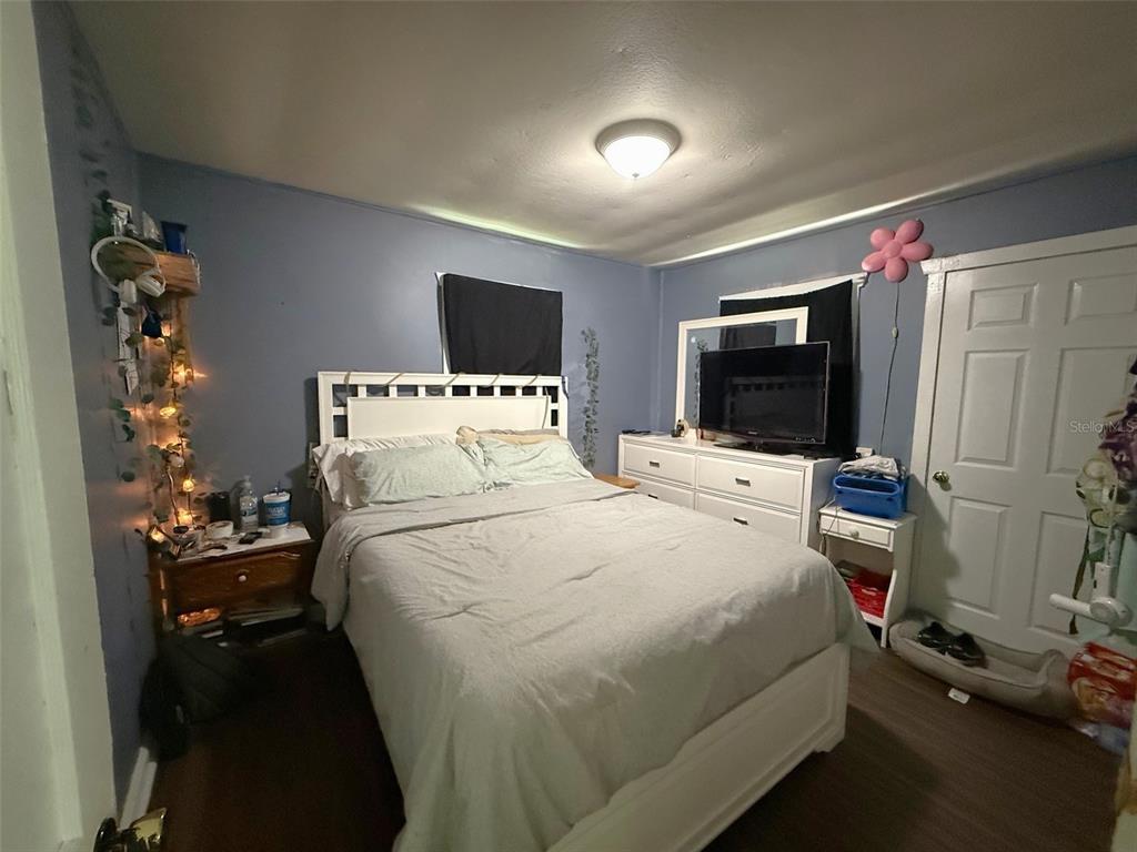 A bedroom features a white bed frame, a white dresser with a television, and blue walls — 1222 GOLCONDA ROAD, LAKELAND, FL