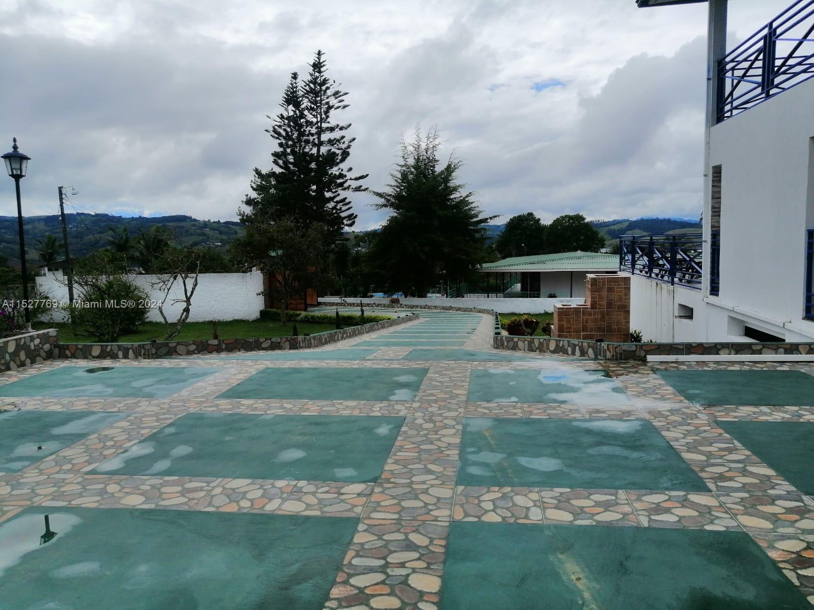 A paved outdoor patio features green rectangular tiles bordered by decorative stone paths — Darien Lago Calima El Darien, 00000, FL