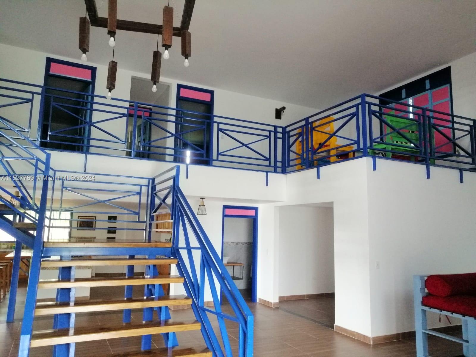 A two-story interior space features a blue metal staircase and matching railings on the loft — Darien Lago Calima El Darien, 00000, FL