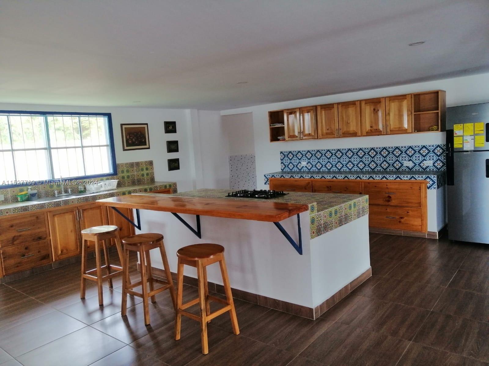 A kitchen features wooden cabinets, a tiled island with a breakfast bar, and dark flooring — Darien Lago Calima El Darien, 00000, FL