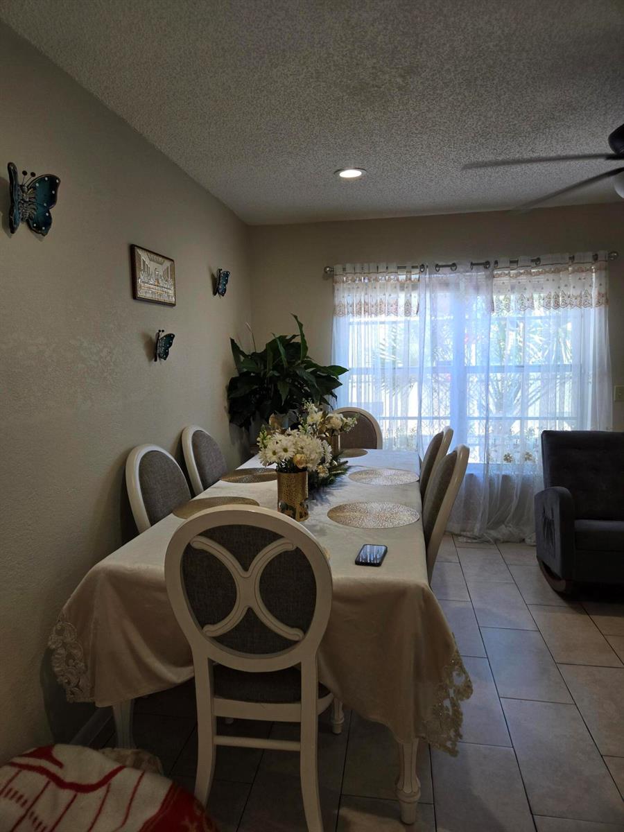 A dining room features a table with chairs, a floral centerpiece, and wall-mounted butterfly decor — 2396 Daphne Drive, West Palm Beach FL 33415, WEST PALM BEACH, FL
