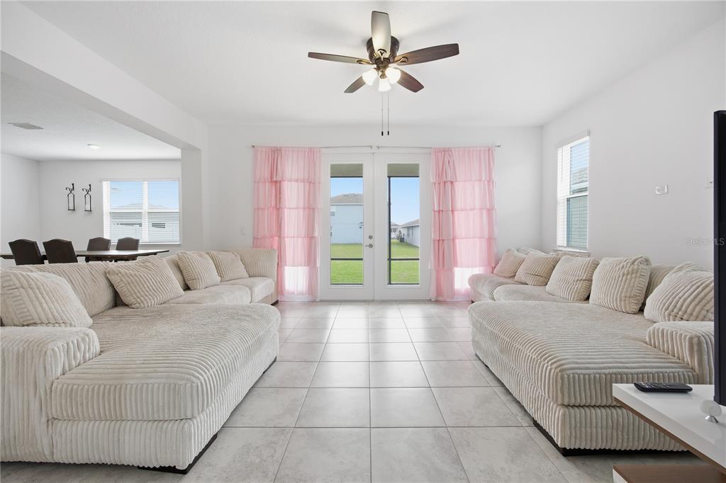 A bright living room features two large white corduroy sectionals, tile flooring, and pink curtains — 7238 SW 60TH LANE, OCALA, FL