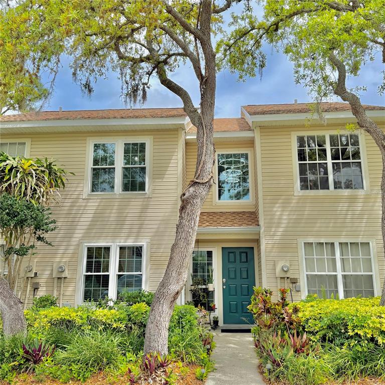 A two-story tan siding townhouse with a teal front door and mature trees — 2122 CLOVER HILL ROAD, PALM HARBOR, FL