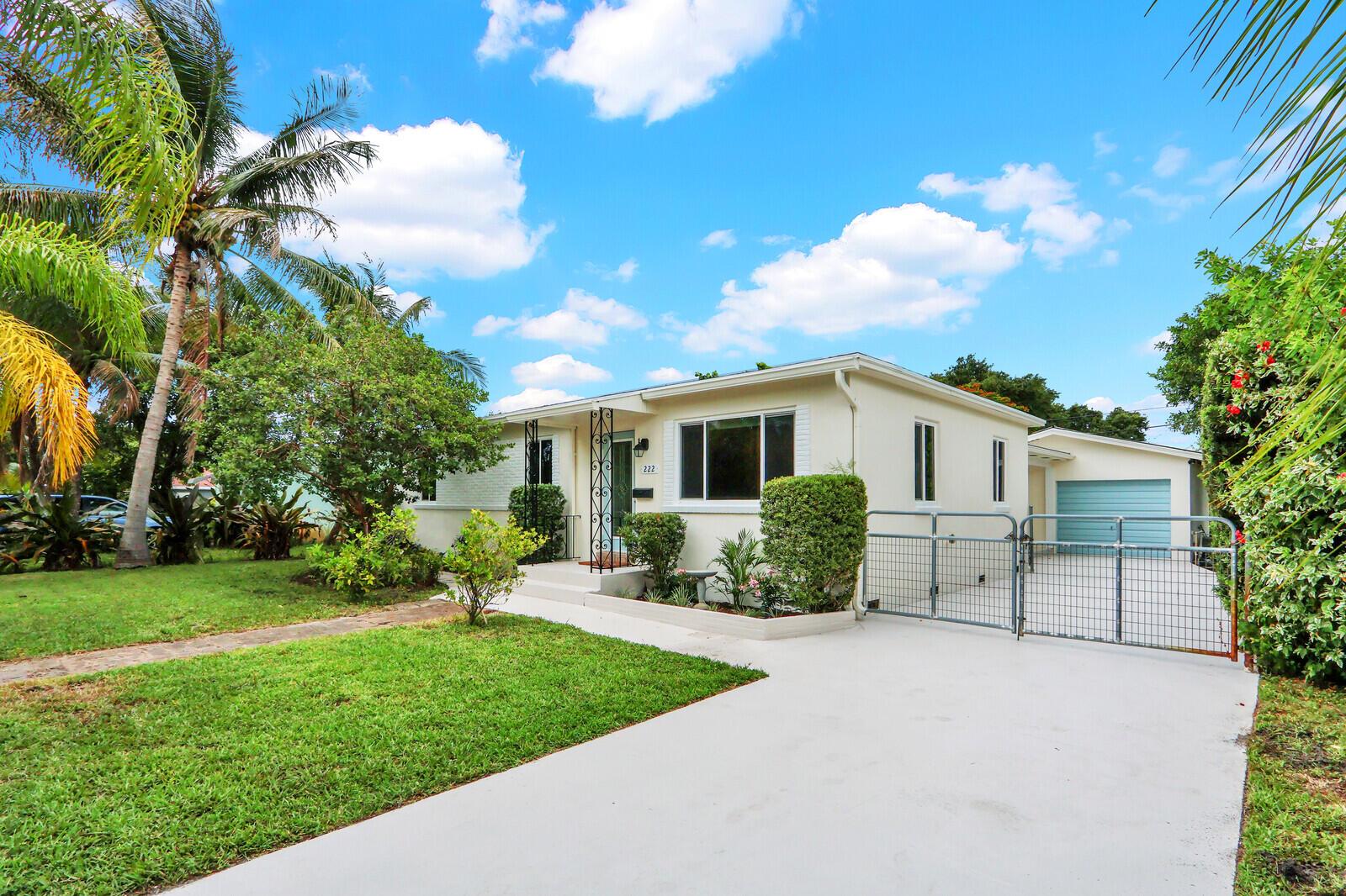 A single-story house with a white exterior, a concrete driveway, and a gated side entrance — 222 Bayberry Drive, Lake Park FL 33403, LAKE PARK, FL