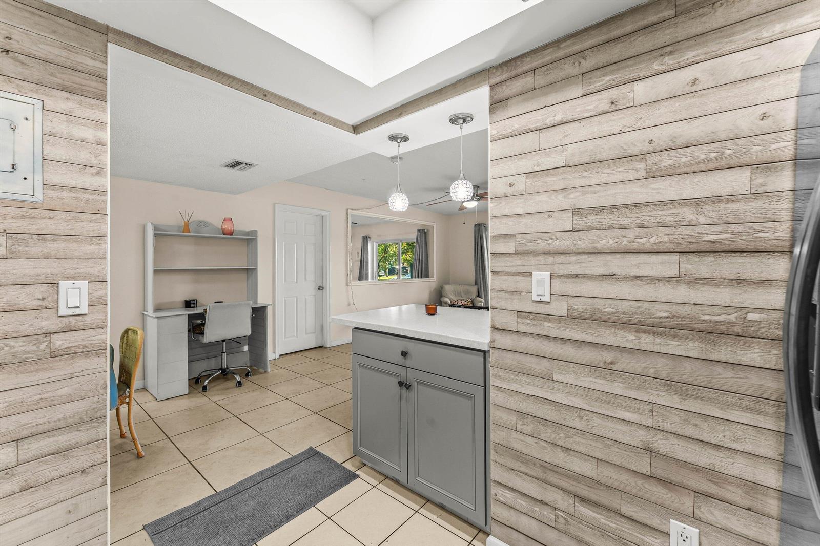 A kitchen with a gray island and wood-paneled walls leads into a home office area — 950 S Kanner Highway # 10, Stuart FL 34994, STUART, FL