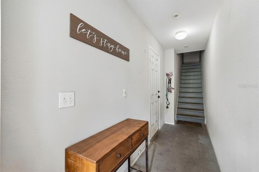 An entryway features a wooden console table, a wall sign, and stairs leading upward — 4755 TUSCAN LOON DRIVE, TAMPA, FL