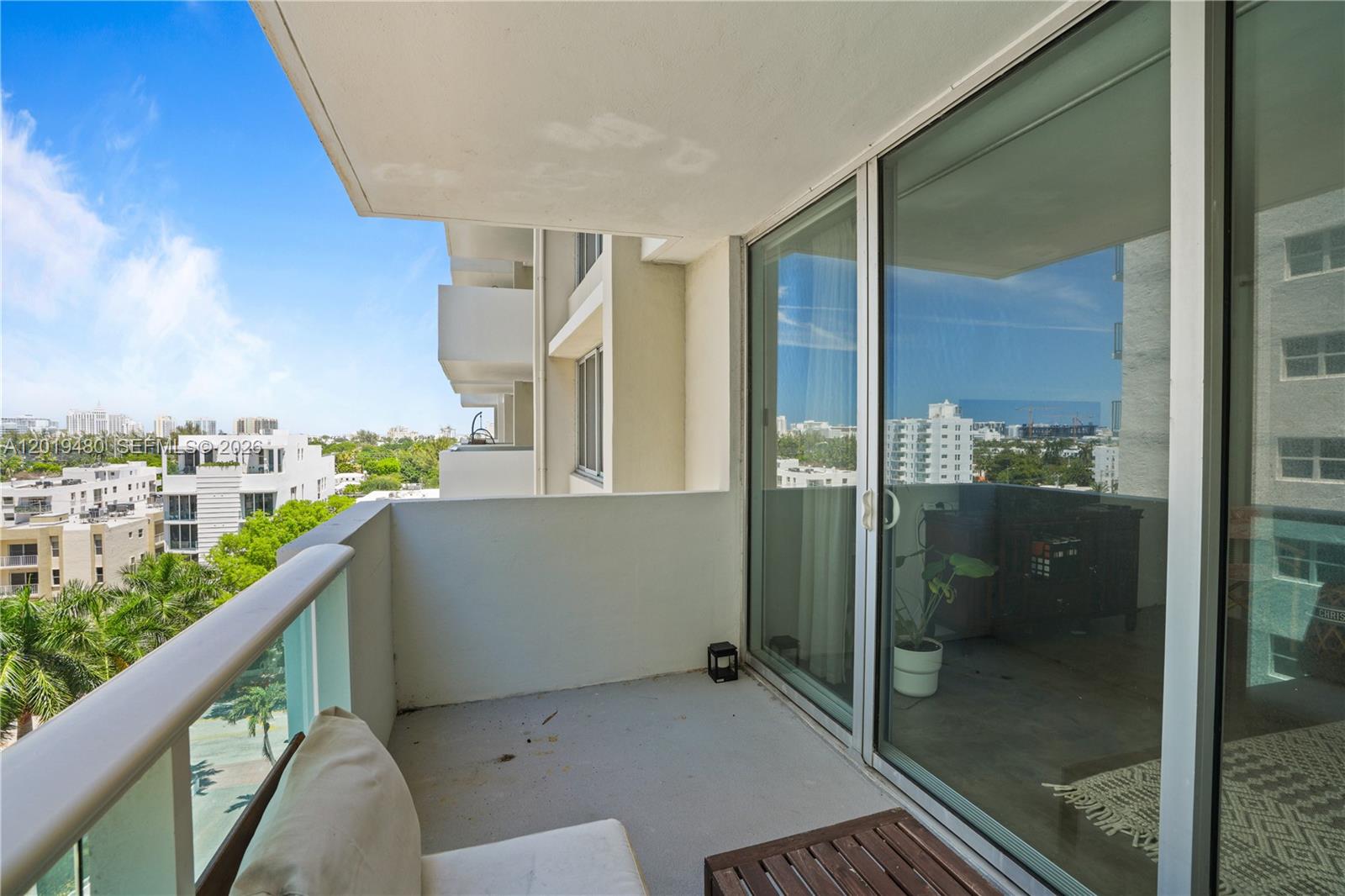 A balcony with a glass railing overlooks a city view with trees and buildings — 1200 West Ave # 819, Miami Beach FL 33139, MIAMI BEACH, FL