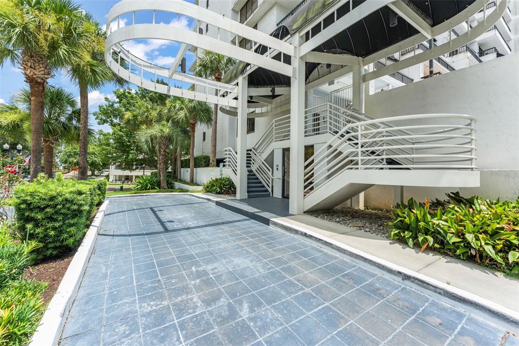 An exterior view of a building entrance featuring a paved driveway and white metal stairs — 530 E CENTRAL BOULEVARD UNIT 503, ORLANDO, FL