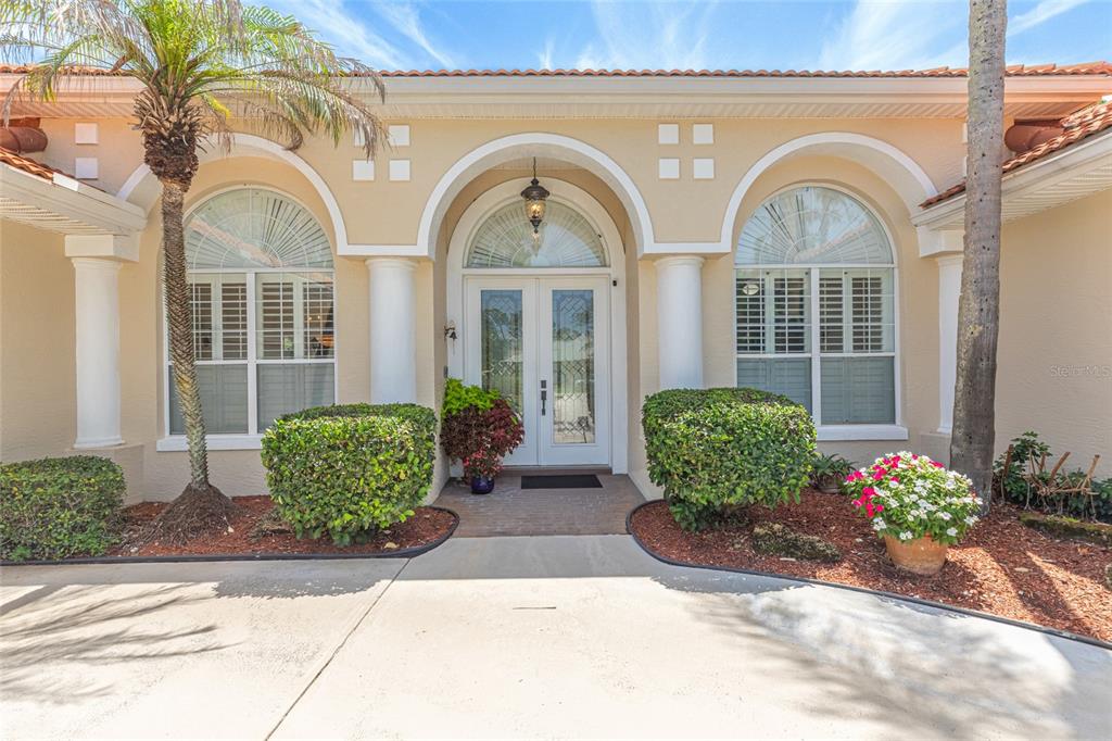 The front exterior of a house features a double door entrance with arched windows — 39 WELLSTREAM LANE, PALM COAST, FL