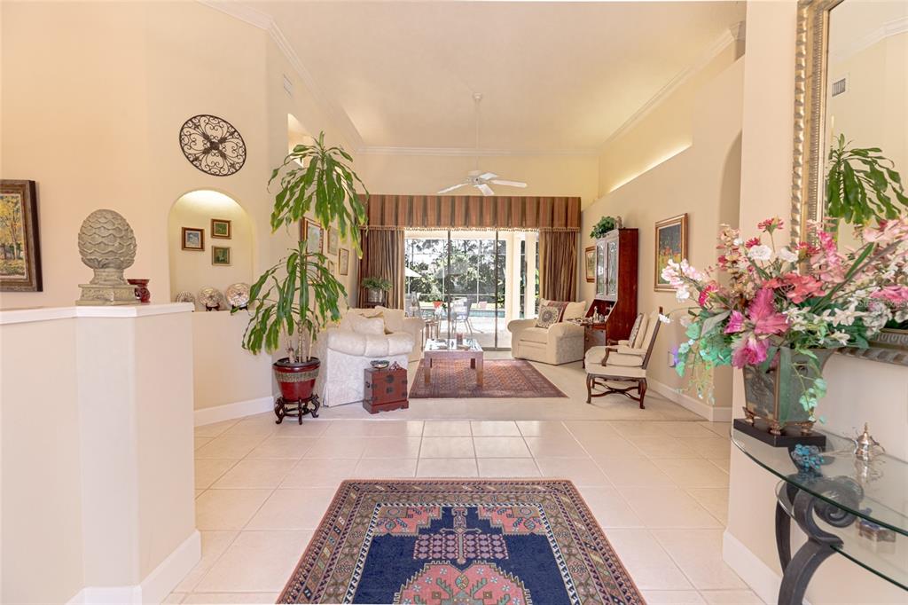 A bright living room features tiled floors, a vaulted ceiling, and a view of a pool — 39 WELLSTREAM LANE, PALM COAST, FL