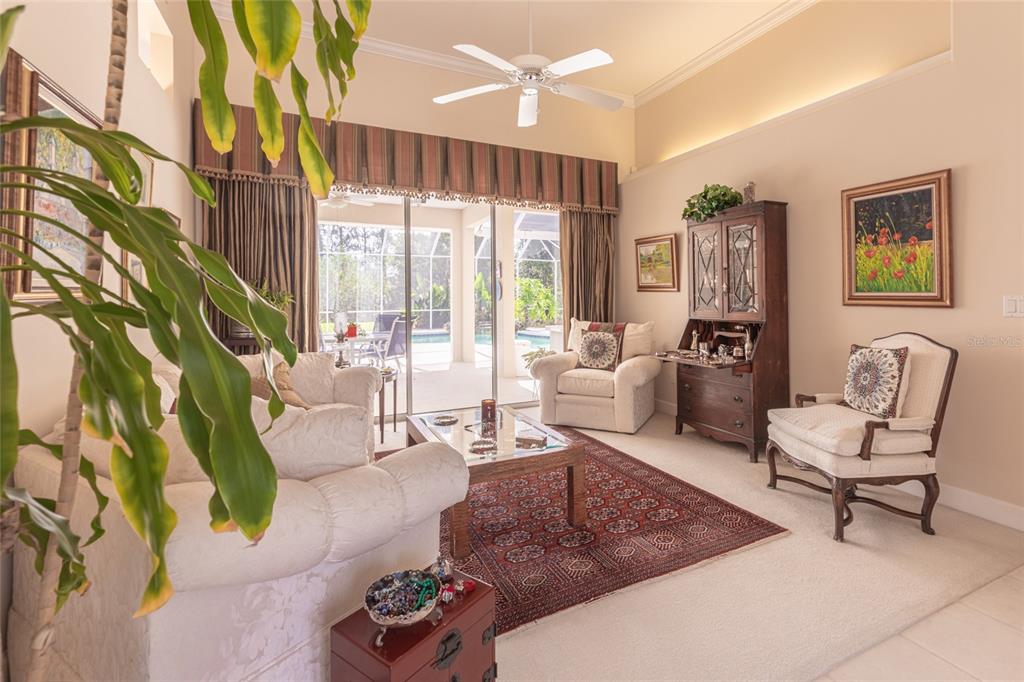 A living room with a white sofa, armchairs, a patterned rug, and a glass coffee table — 39 WELLSTREAM LANE, PALM COAST, FL