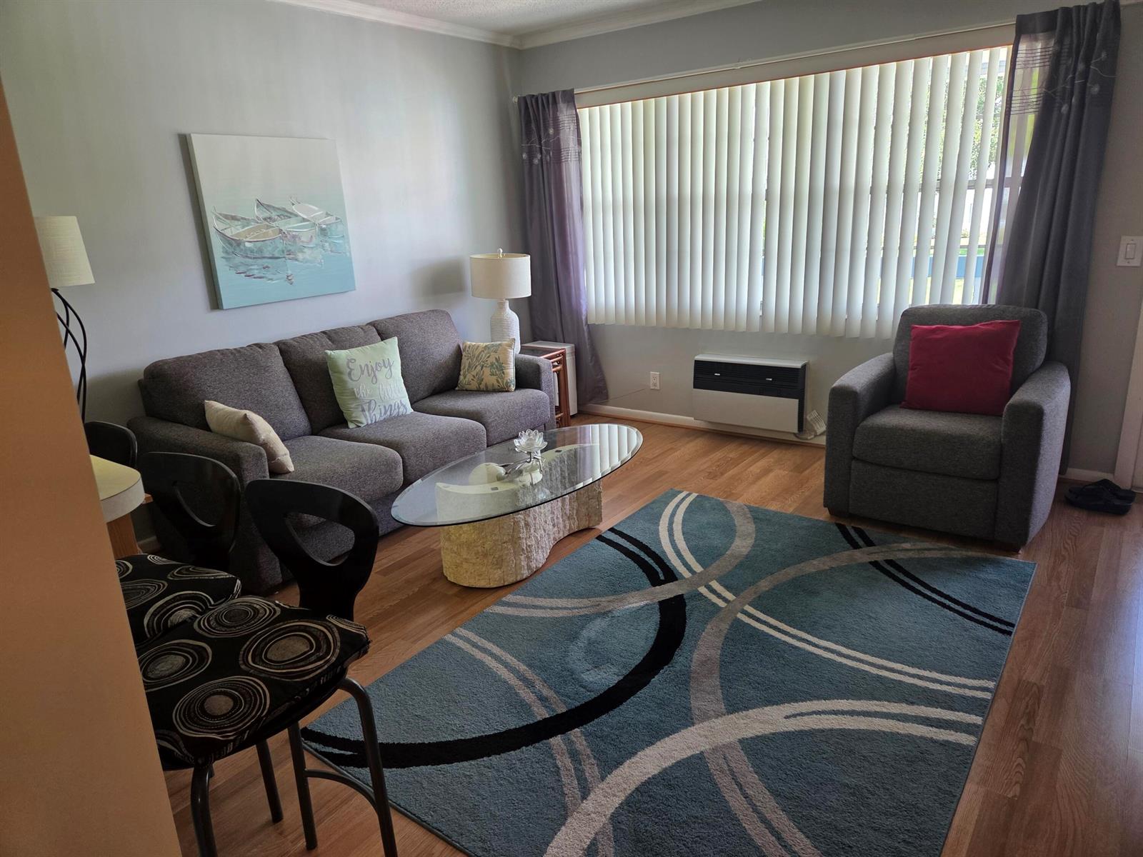 A living room features a gray sofa, an armchair, a glass coffee table, and a rug — 138 Newport I, Deerfield Beach FL 33442, DEERFIELD BEACH, FL