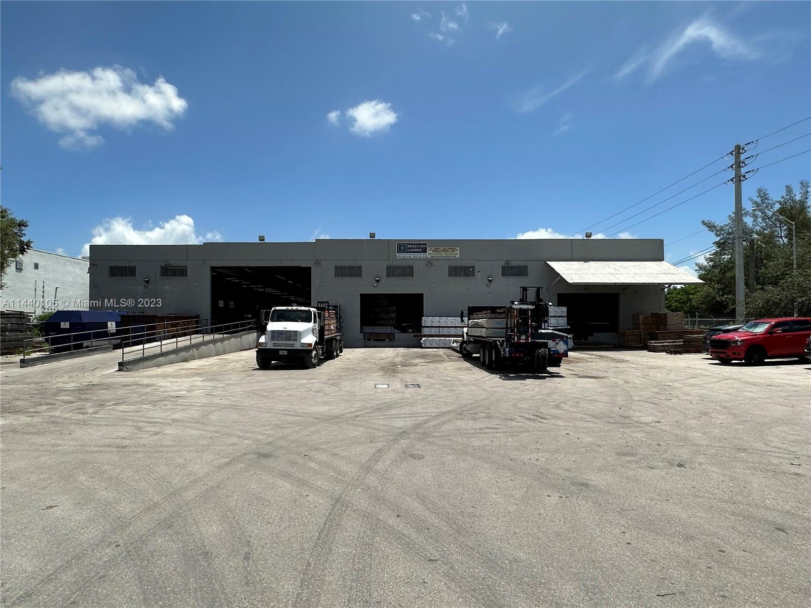 An exterior view of a commercial warehouse building with two trucks parked in the lot — 775 NW 71st St, Miami FL 33150, MIAMI, FL