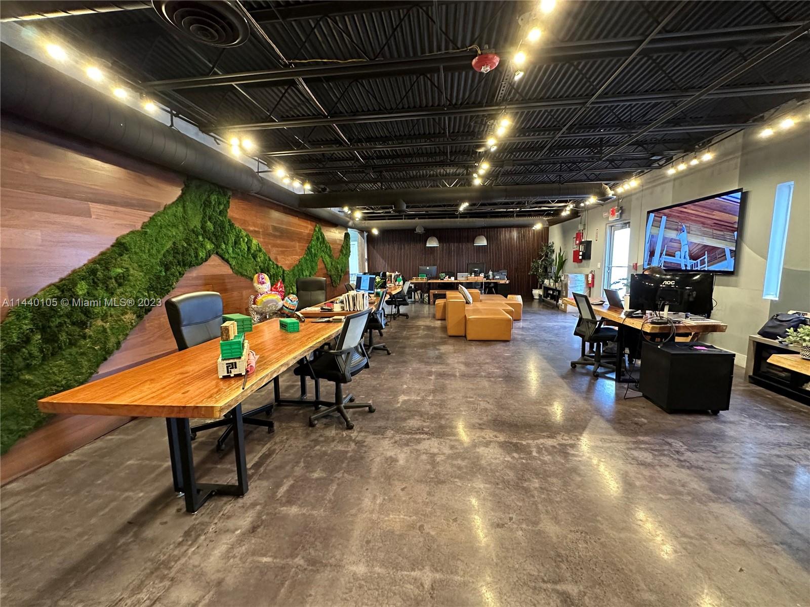 This open-concept office features a live-edge wooden desk, a moss wall, and concrete flooring — 775 NW 71st St, Miami FL 33150, MIAMI, FL