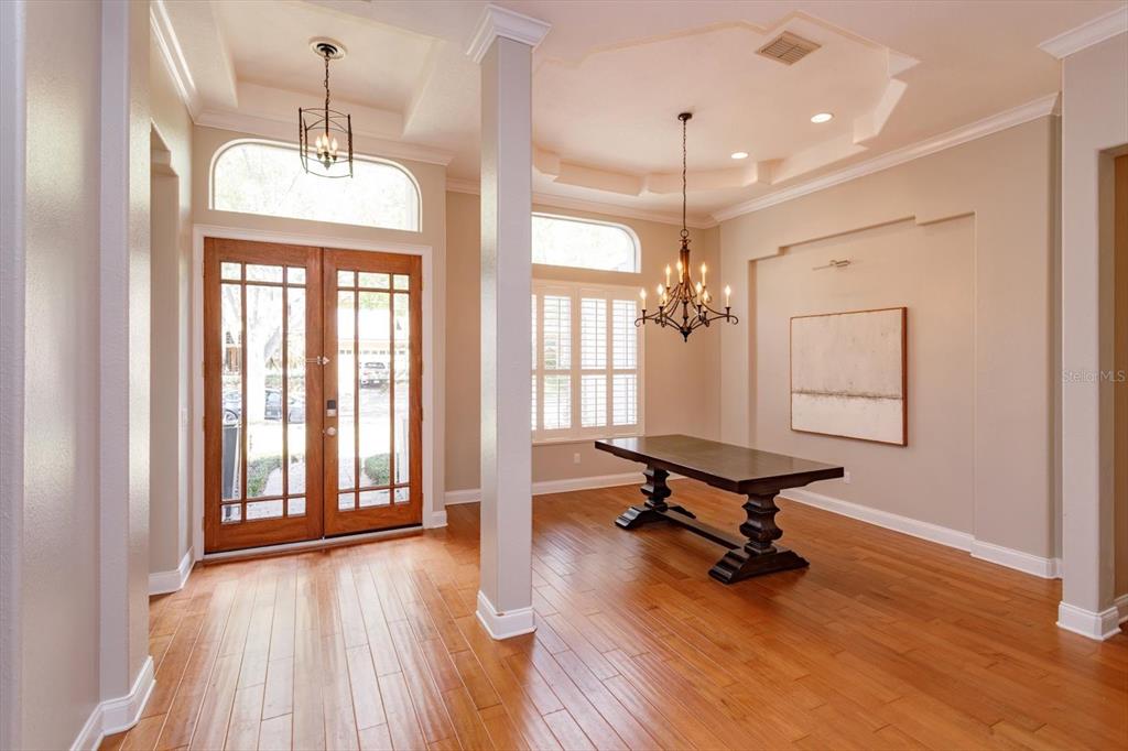 A foyer with hardwood floors, a dining table, and a chandelier near double glass doors — 8816 GREAT COVE DRIVE, ORLANDO, FL