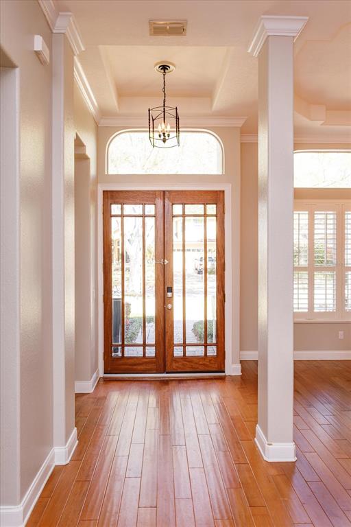 A foyer with hardwood floors, a tray ceiling, and double glass-paneled wooden front doors — 8816 GREAT COVE DRIVE, ORLANDO, FL