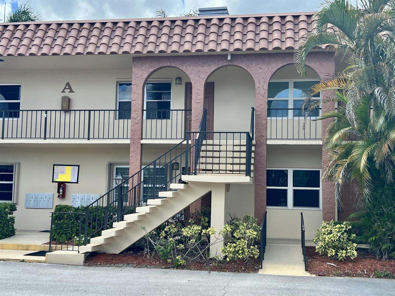 A two-story apartment building exterior features a tiled roof, arched entryway, and outdoor staircase — 2600 S Kanner Highway # A4, Stuart FL 34994, STUART, FL