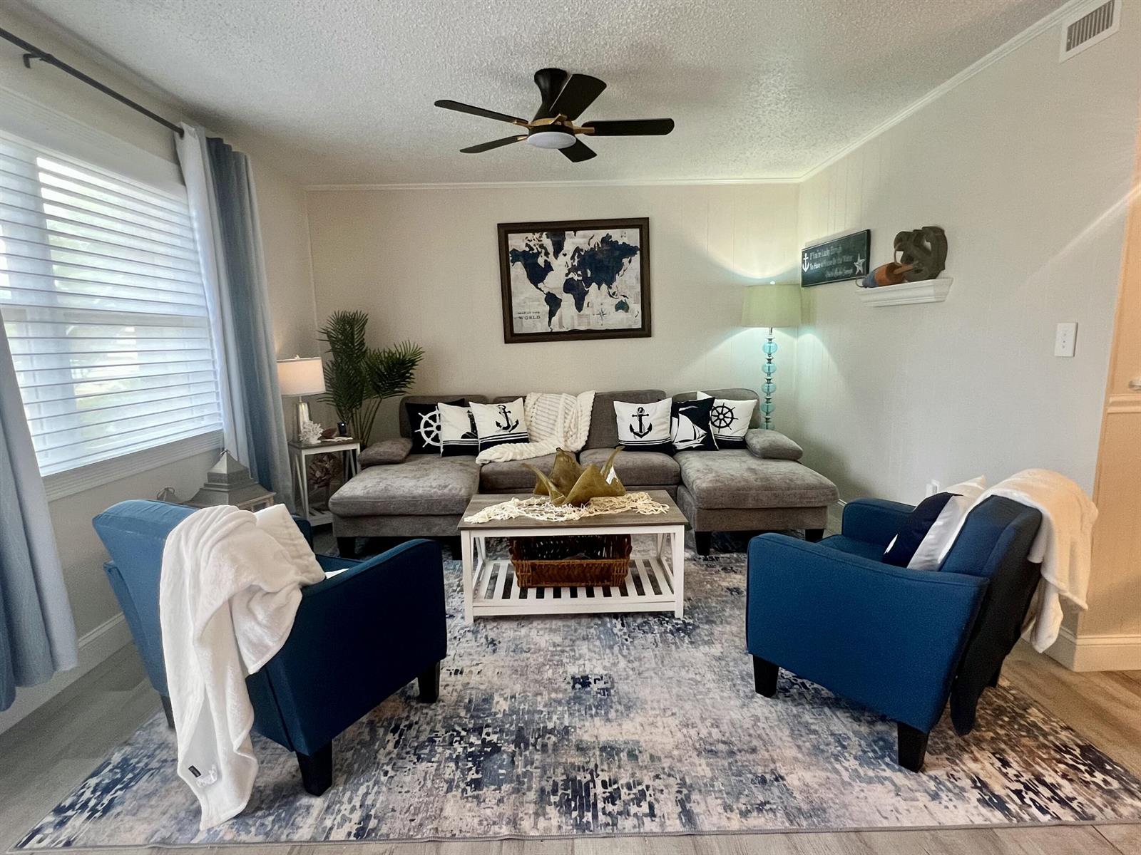 A living room features a grey sectional sofa, two blue armchairs, and nautical-themed decor — 2600 S Kanner Highway # A4, Stuart FL 34994, STUART, FL
