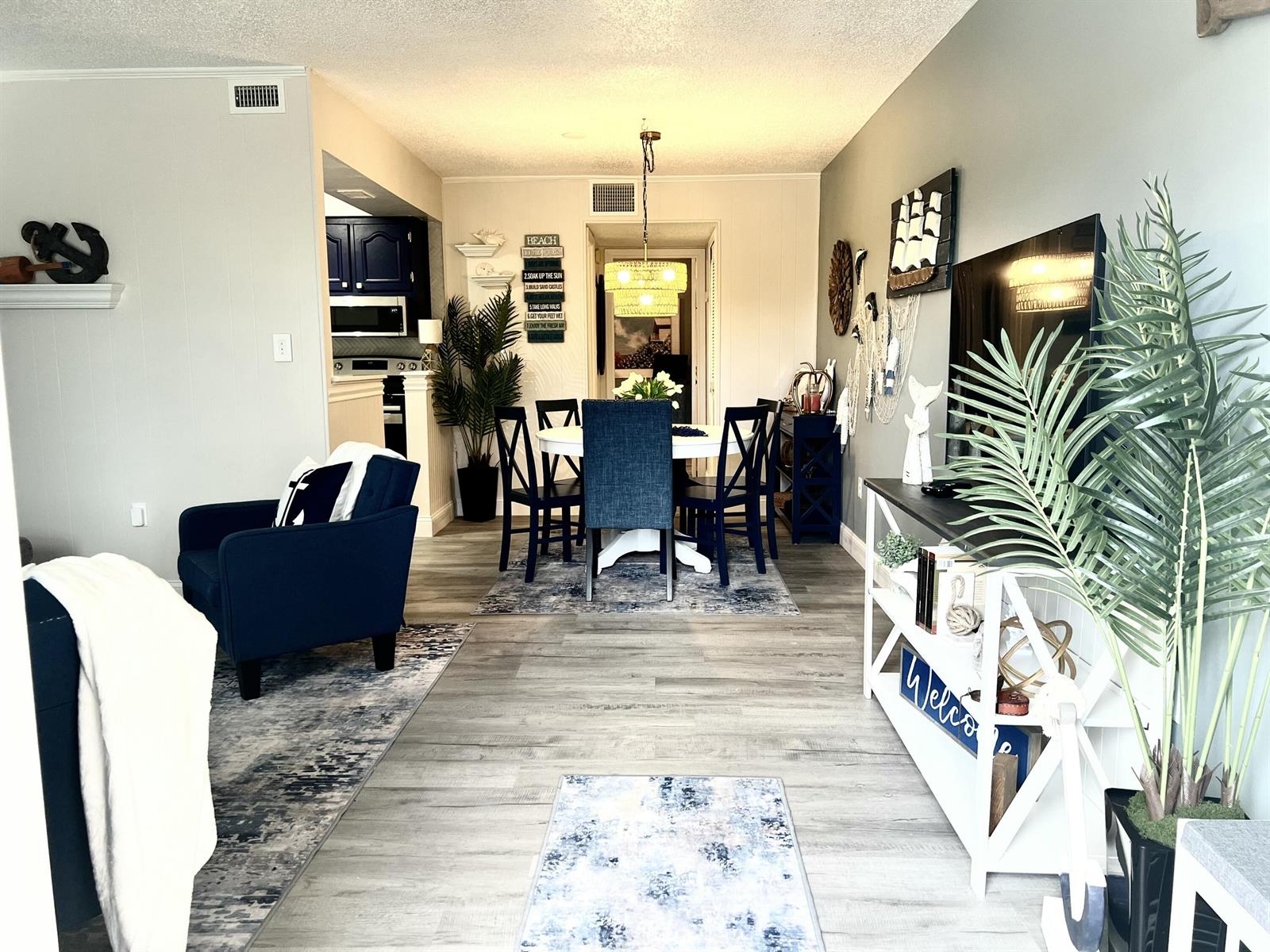 A living and dining area features light wood-look flooring, navy blue furniture, and coastal decor — 2600 S Kanner Highway # A4, Stuart FL 34994, STUART, FL