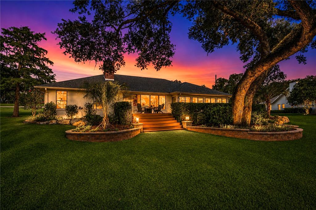 A single-story house with a wooden deck and stone retaining walls at sunset — 5101 NW 80TH AVENUE ROAD, OCALA, FL