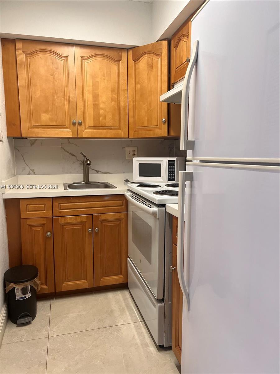 A small kitchen features light wood cabinets, a white stove, and a white refrigerator — 5201 NW 7th St # 314, Miami FL 33126, MIAMI, FL