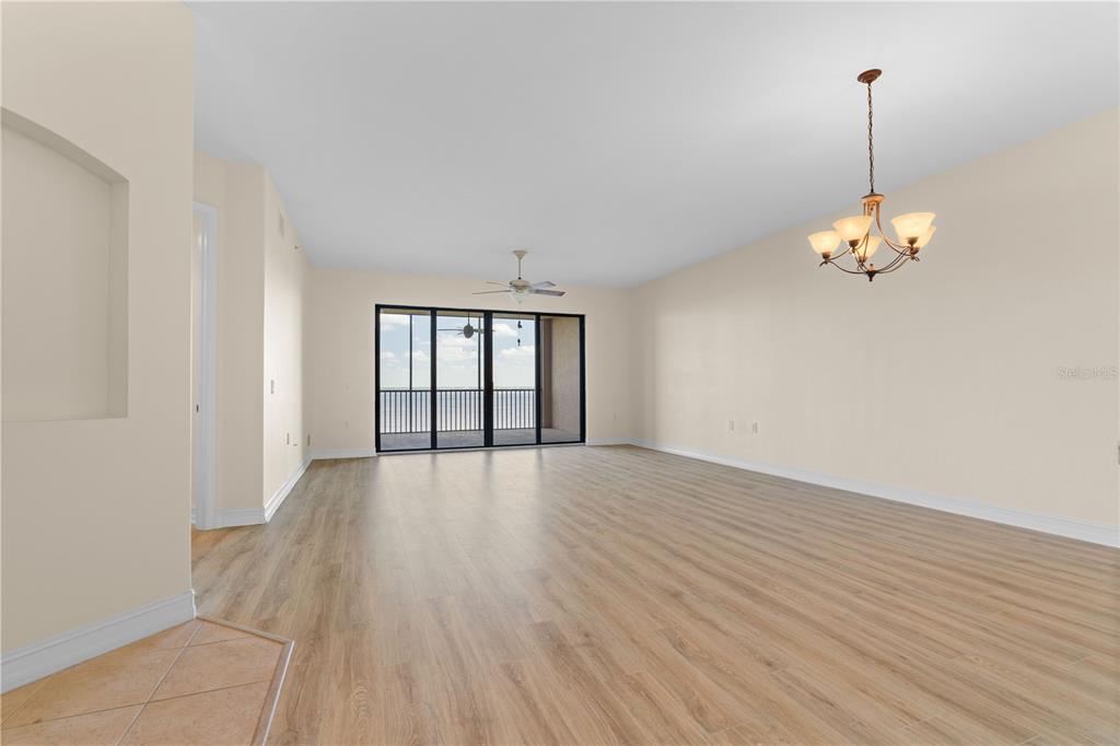 An empty living room with light wood-look flooring, a ceiling fan, and a sliding glass door — 89 VIVANTE BOULEVARD UNIT 8942, PUNTA GORDA, FL