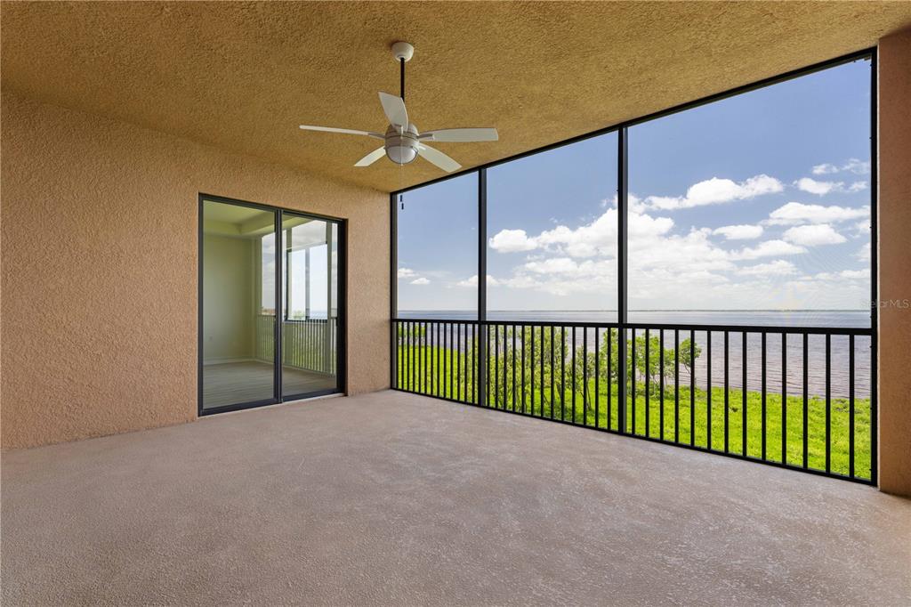 A covered balcony with a ceiling fan, screen enclosure, and a view of the water — 89 VIVANTE BOULEVARD UNIT 8942, PUNTA GORDA, FL