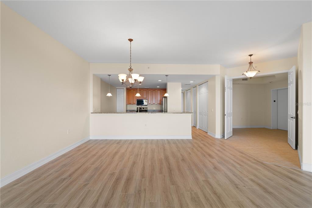 A living area with wood-look flooring opens to a kitchen with a breakfast bar — 89 VIVANTE BOULEVARD UNIT 8942, PUNTA GORDA, FL